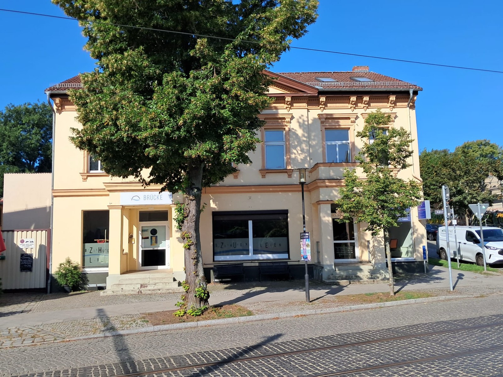 Das Gemeindehaus „Brücke“ in der Schleusenstraße: gelber Altbau mit BRÜCKE-Schild über dem Eingang und dem Schriftzug „Beziehungen leben“ im Schaufenster