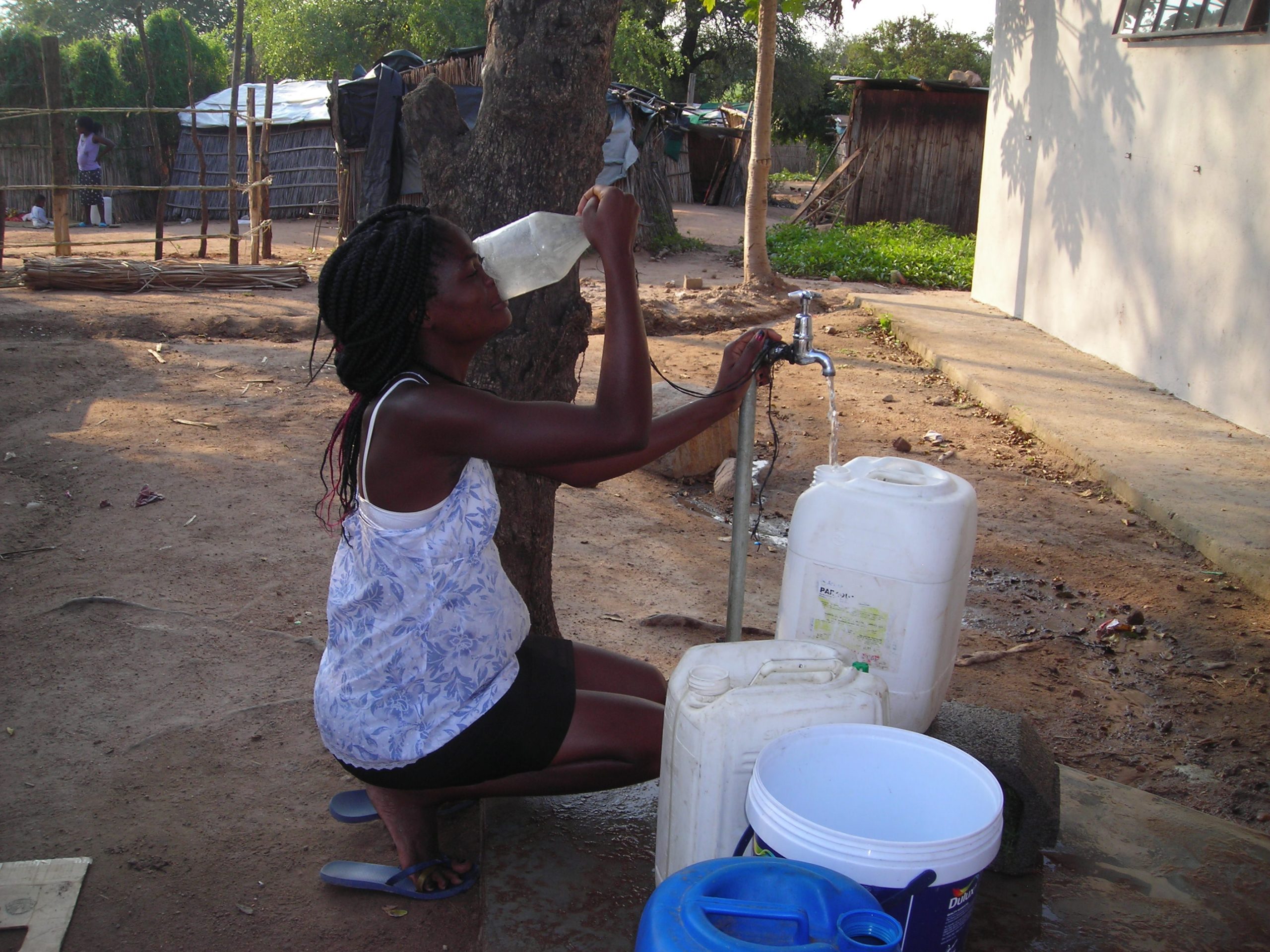 Eine Frau trinkt Wasser, das sie aus einem neugebauten Brunnen entnahm.