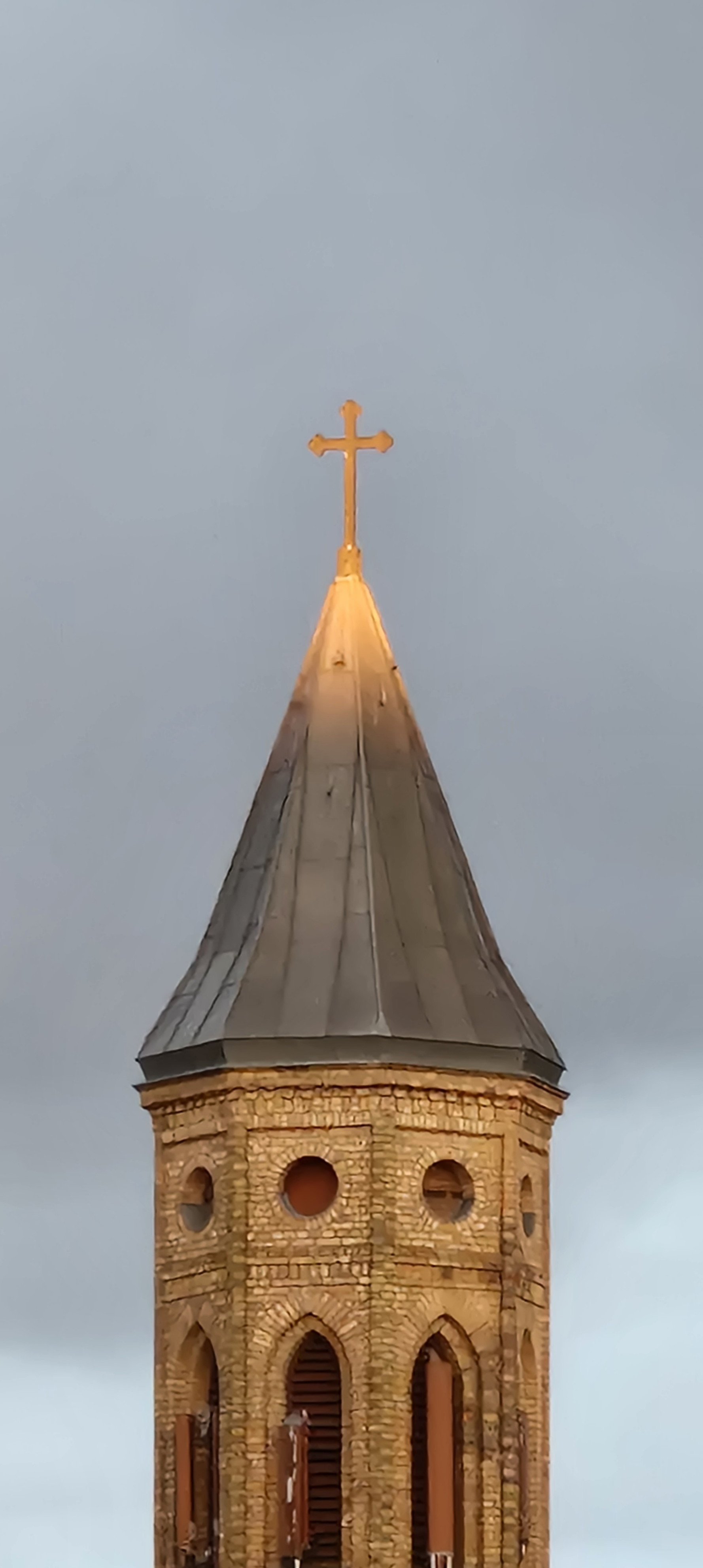 Von Sonne beleuchtetes Kreuz auf einem Kirchturm